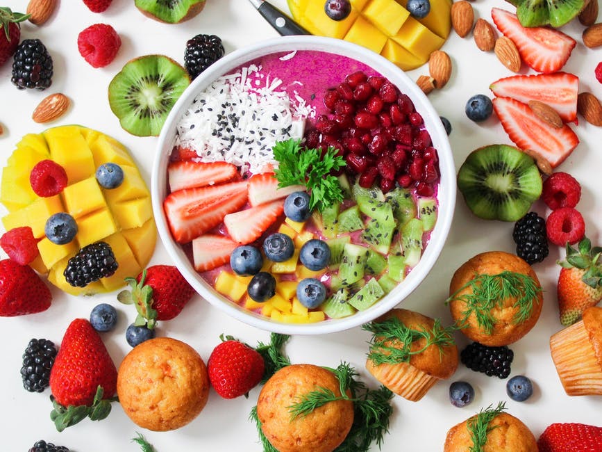 Fruits frais dans un bol, avec autres fruits et muffins à côté